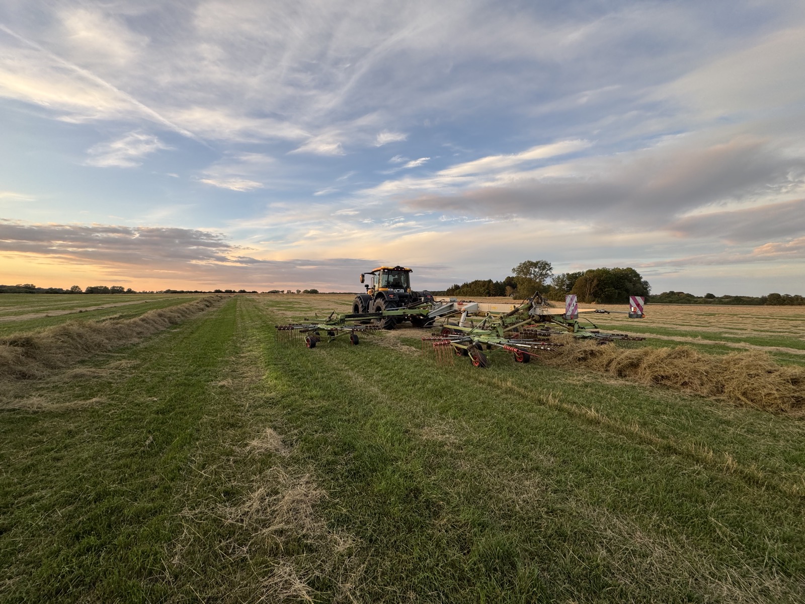 Traktor med rive ved solnedgang